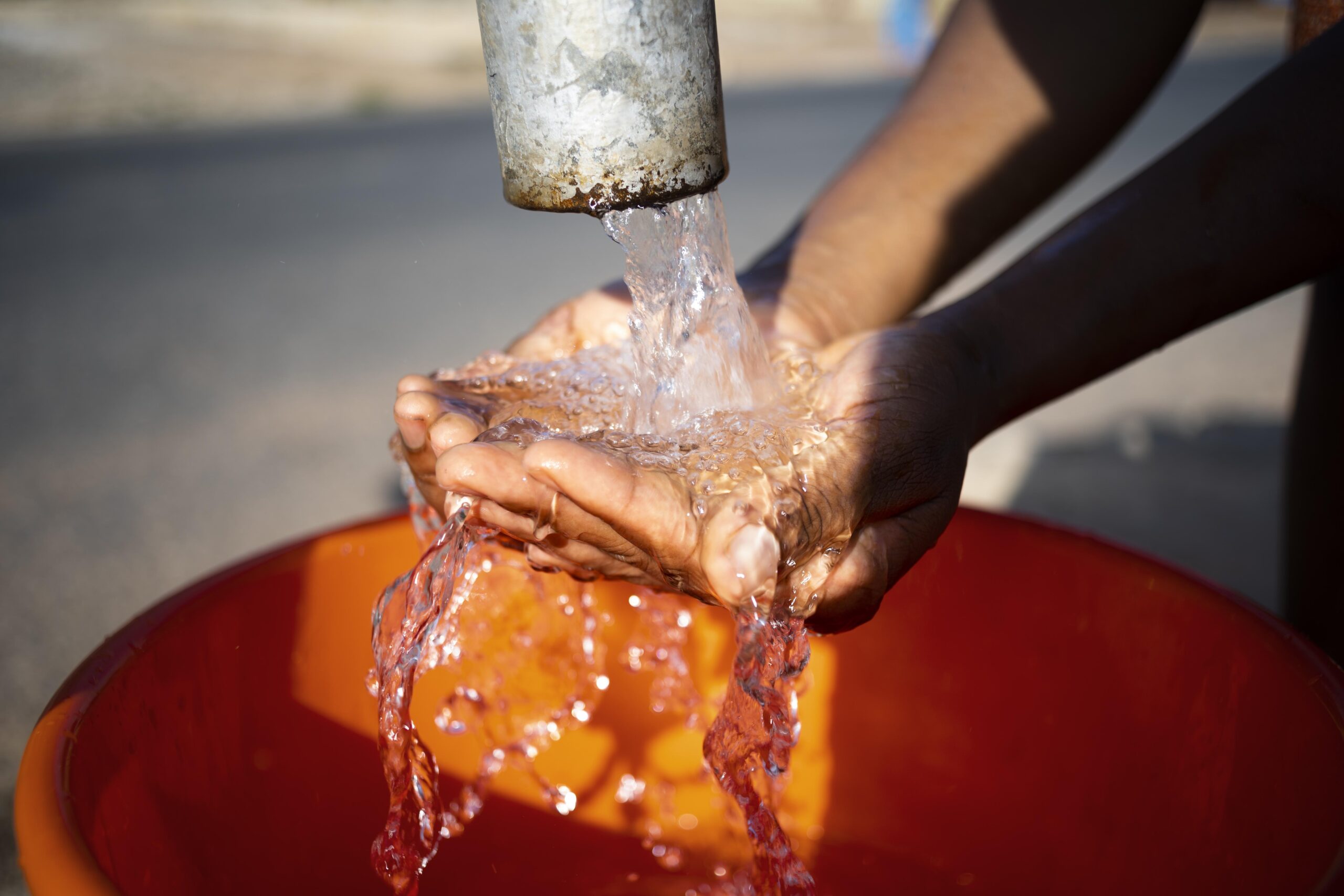 mujer-africana-vertiendo-agua-recipiente-al-aire-libre